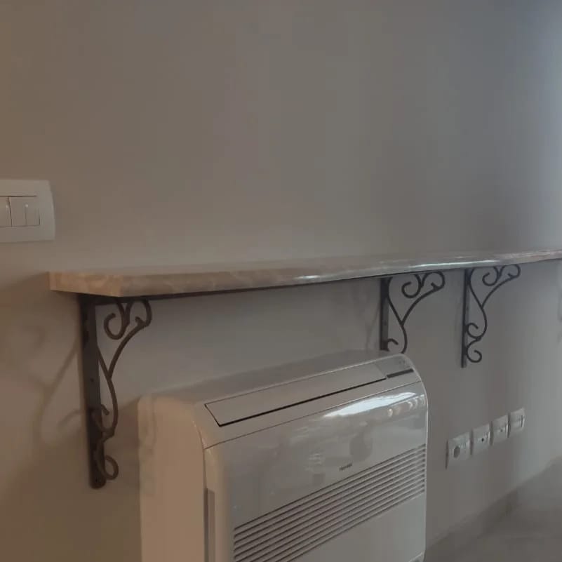 Konzola metalike me spirale nën raftin e murit